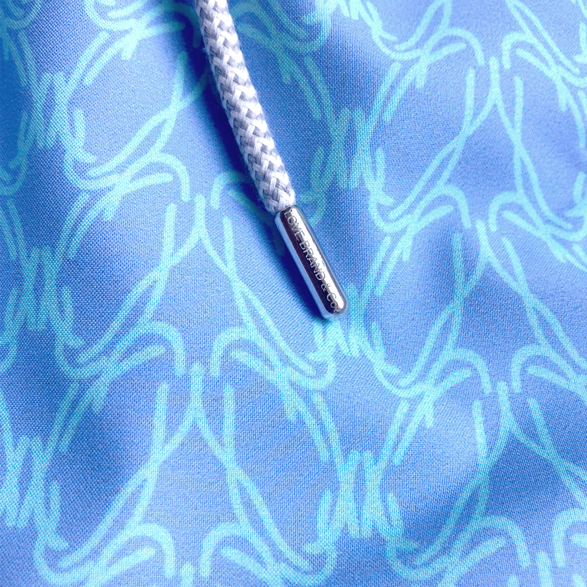 Close-up view of Boys Posidonia y el Mar Staniel Swim Shorts, featuring a blue fabric with light blue Posidonia Oceanica-inspired print and a white drawstring.
