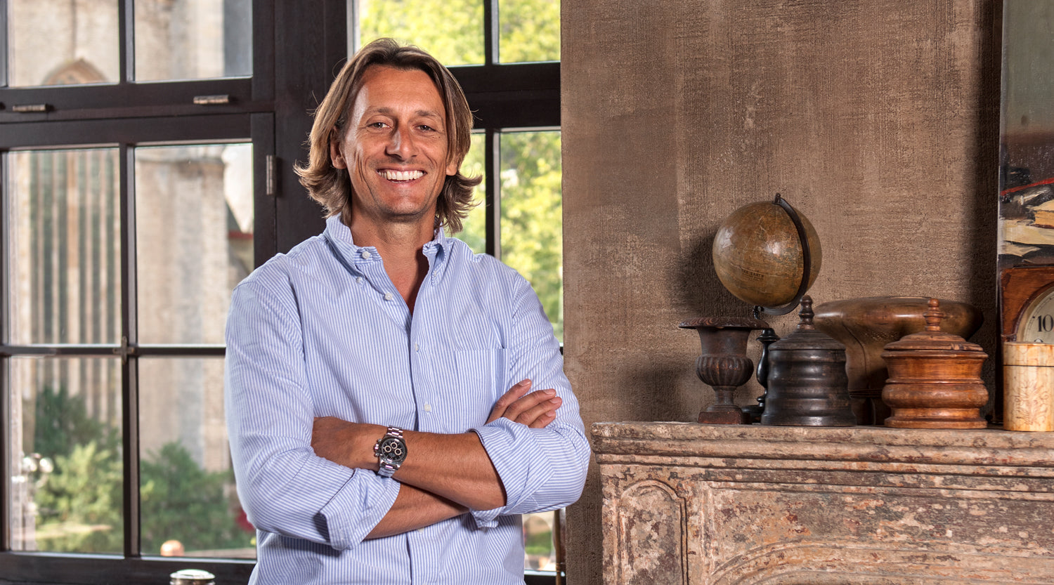 Arnaud Zannier standing in a room with large windows and decorative items on a shelf.
