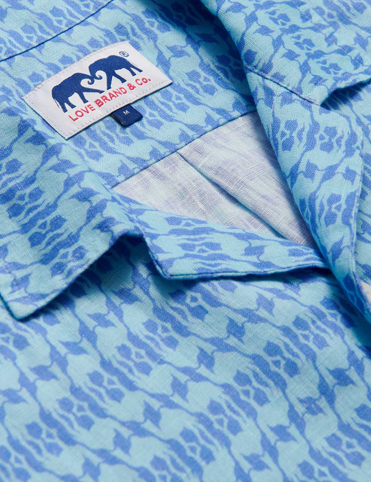 Close-up of the Men's Camel Mirage Sky Arawak Linen Shirt, showcasing its unique blue pattern and the Love Brand & Co. label.