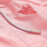 Close-up of pastel pink swim shorts featuring coral embroidery. Embroidered swim shorts with a braided drawstring with a metallic tip.