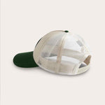 Trucker cap in stone and forest green with mesh back, adjustable strap, and slightly curved visor.