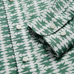 Close-up of the Men's Dolphins of Greece Abaco Linen Shirt, showcasing the green and white dolphin print, button-down front, and classic collar with signature engraved corozo nut buttons.