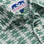 Close-up of the Men's Dolphins of Greece Abaco Linen Shirt showcasing the green and white dolphin print with a visible Love Brand & Co. label. Old money shirts made from 100% cotton.