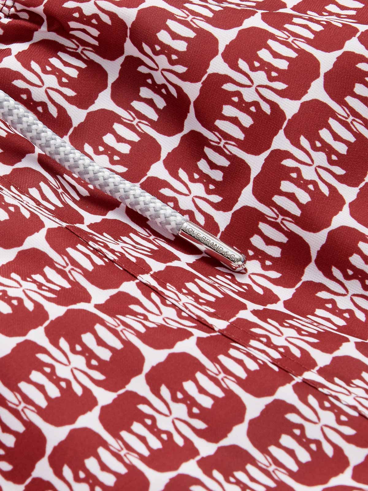 Close-up view of Men's Elephants of India Staniel Swim Shorts showing dark burgundy elephant pattern on a crisp white background with a white drawstring.