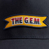 Navy blue trucker cap with "The G.E.M." logo label on the front.