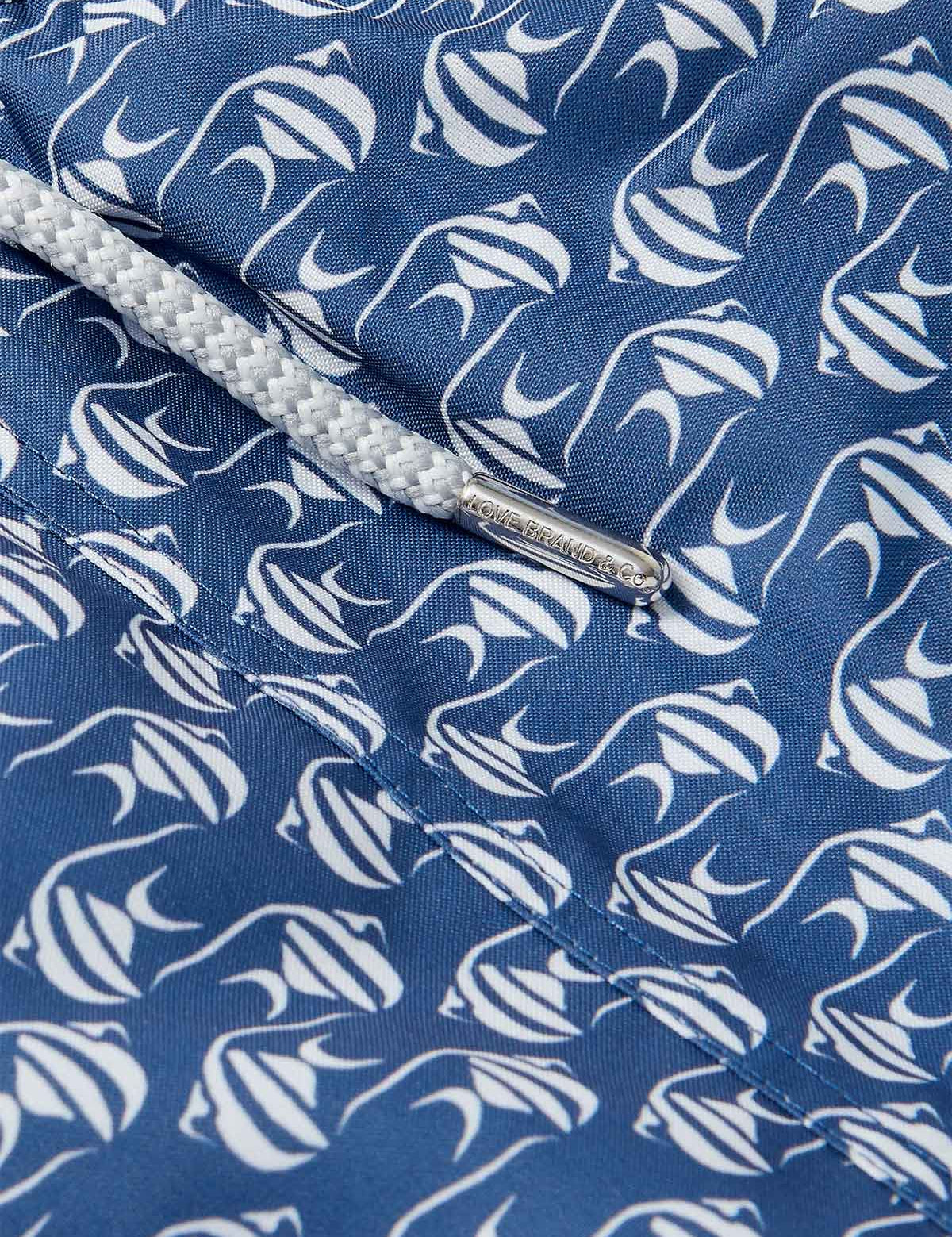 Go With The Flow mens swim shorts detail. The design features a print of white Moorish Idol Fish on a blue background.