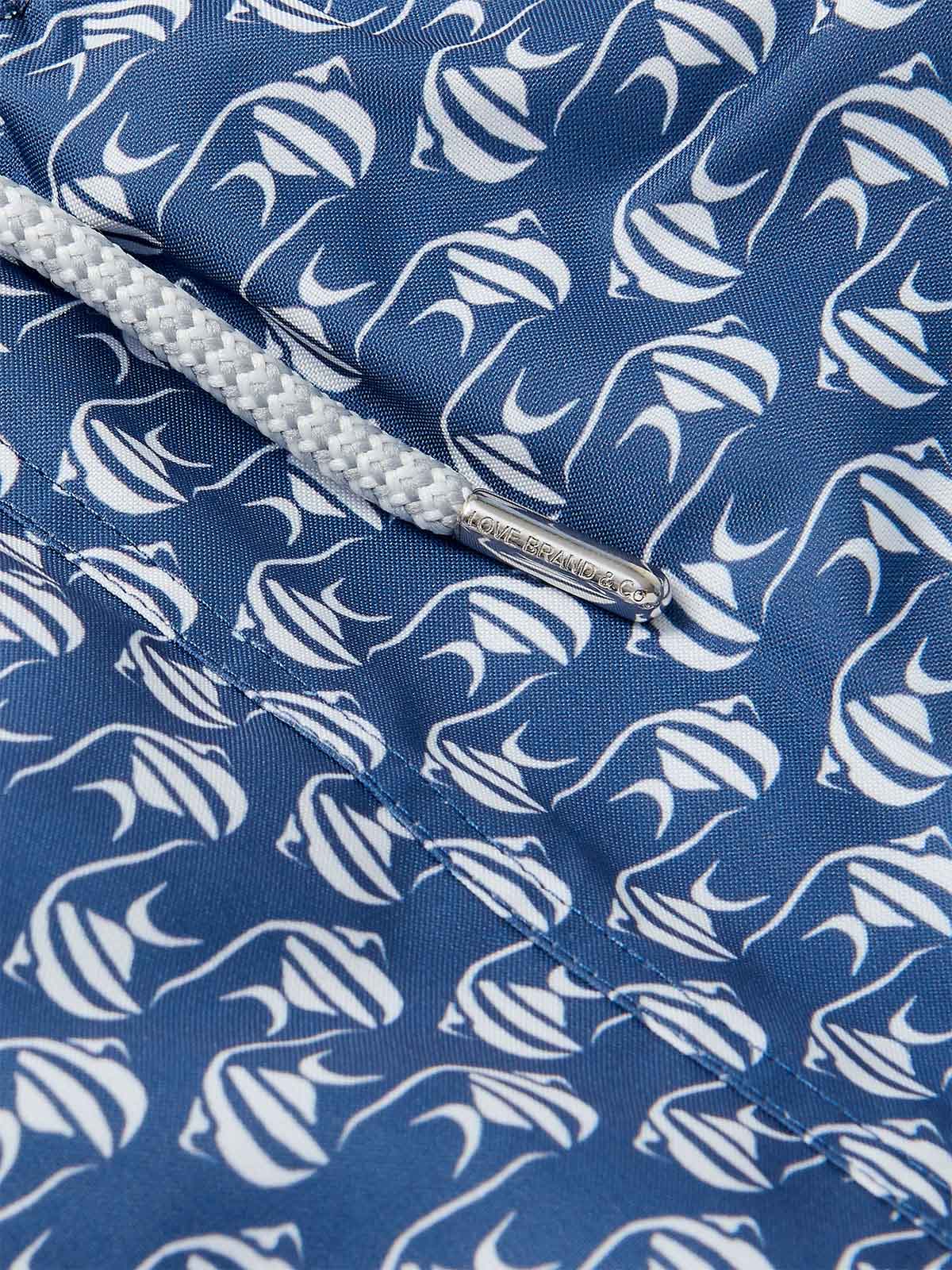 Close-up of Men's Go With the Flow Staniel Swim Shorts. Patterned swim shorts featuring a Moorish Idol fish print on a deep blue background.