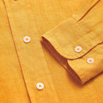 Close-up view of the Men's Golden Hour Abaco Linen Shirt showcasing the button details and linen texture in a warm golden color.