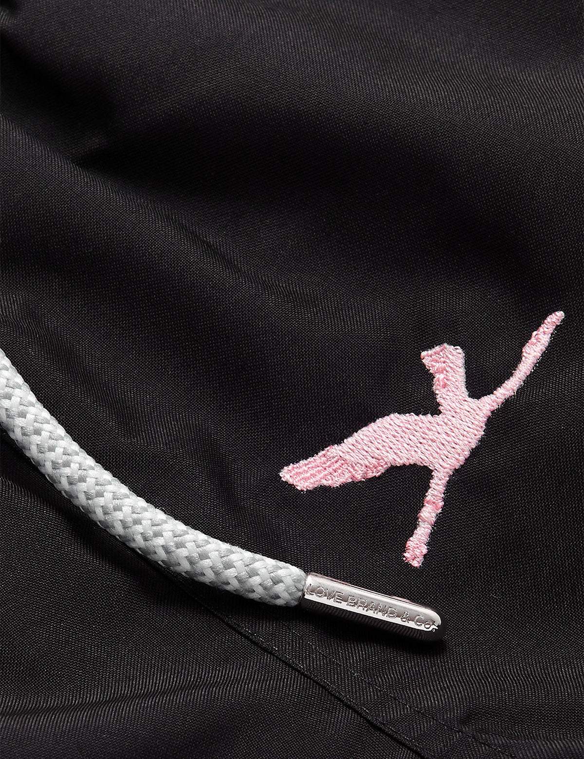 Close-up view of the Boys Lake Nakuru Staniel Swim Shorts, featuring a pink embroidered flamingo and a grey drawstring with metallic tips.
