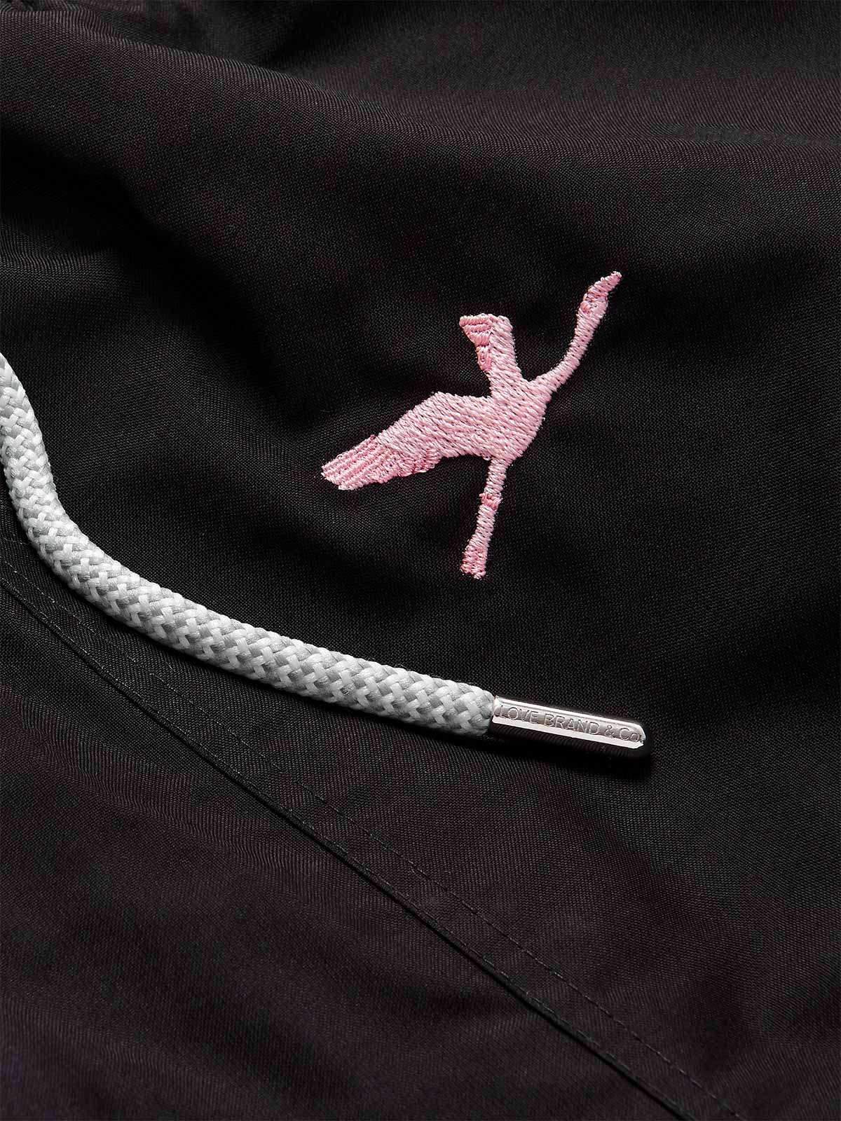 Close-up of Men's Lake Nakuru Embroidered Staniel Swim Shorts. Patterned swim shorts with pink flamingo embroidery and grey drawstring.