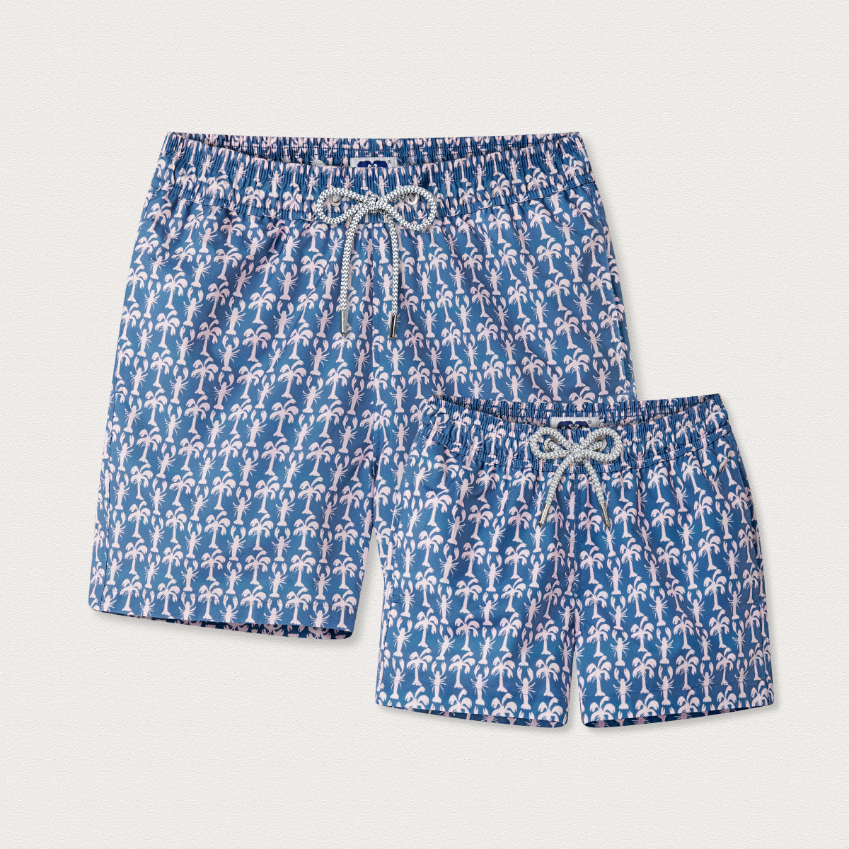 Blue swim shorts with pink palm tree pattern on a light grey background