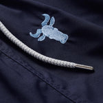 Navy blue men's swim shorts with intricate sky blue embroidered wildebeest design and white drawstring detail.