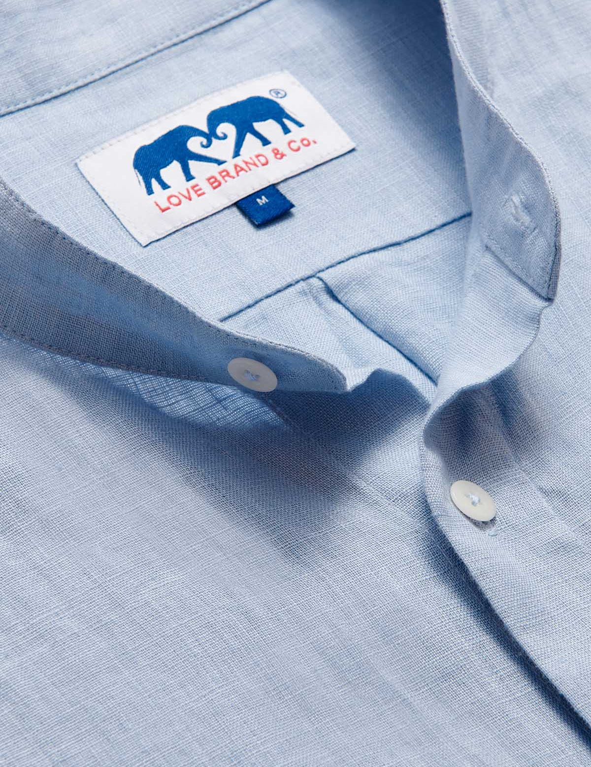 Close-up view of the Men's Elephant Palace Sky Maycock Linen Shirt showcasing the collar, buttons, and the Love Brand & Co. label with an elephant design.