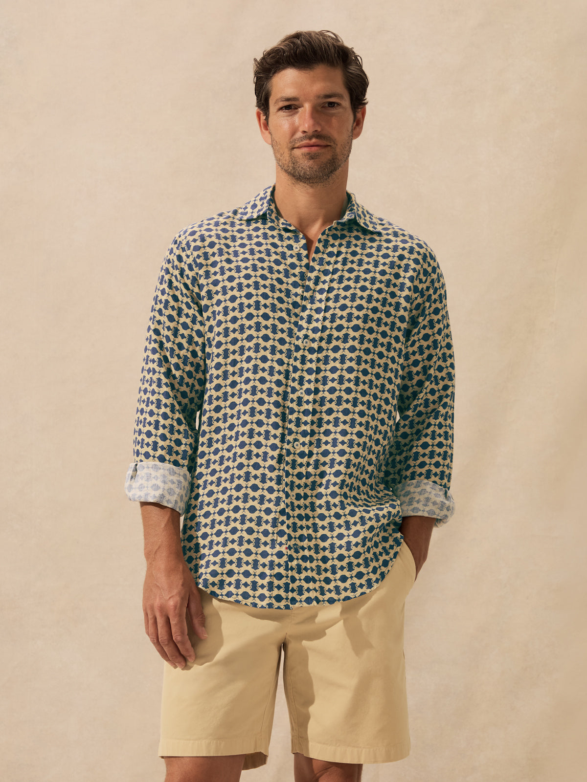 A man wearing a long-sleeve button-up shirt with a blue and beige geometric pattern.