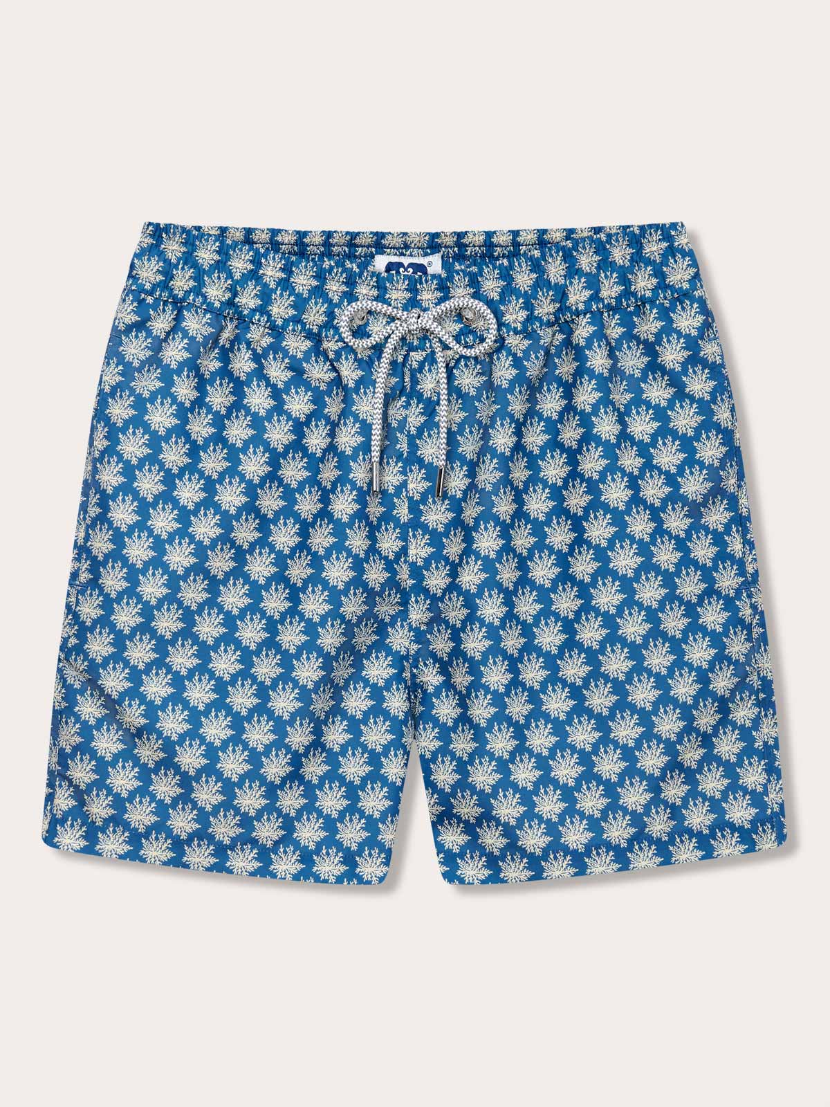Men's Coral Clusters Staniel Swim Shorts featuring a luxurious stone-shaded coral design. Patterned swim shorts on a blue background crafted from 100% recycled materials with a drawstring closure.
