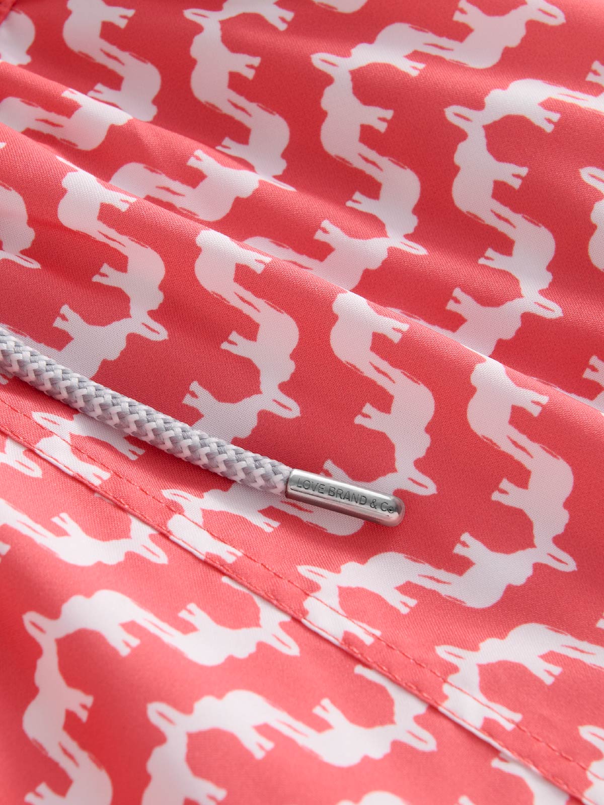 Close-up of a red fabric with white elephant pattern and a metal drawstring
