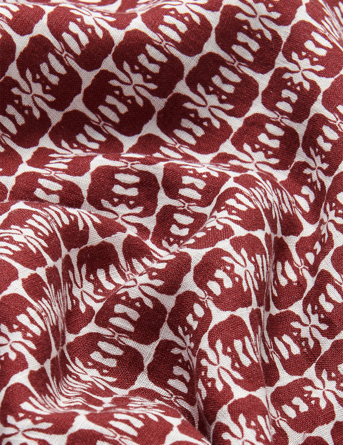 Close-up view of men's Joulter Linen Shorts featuring a pattern of dark burgundy elephants on a white background.