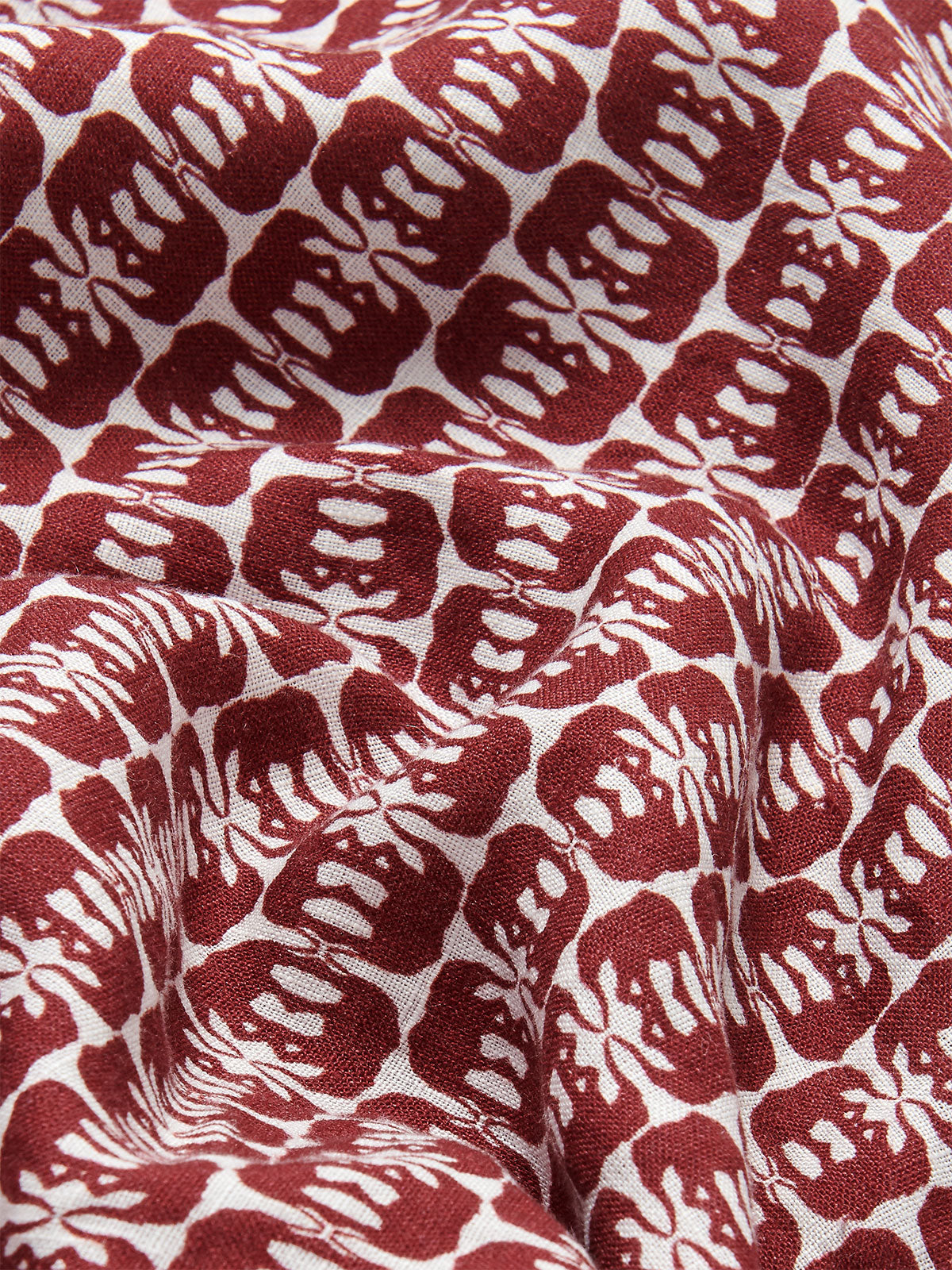 Close-up view of men's Joulter Linen Shorts featuring a pattern of dark burgundy elephants on a white background.