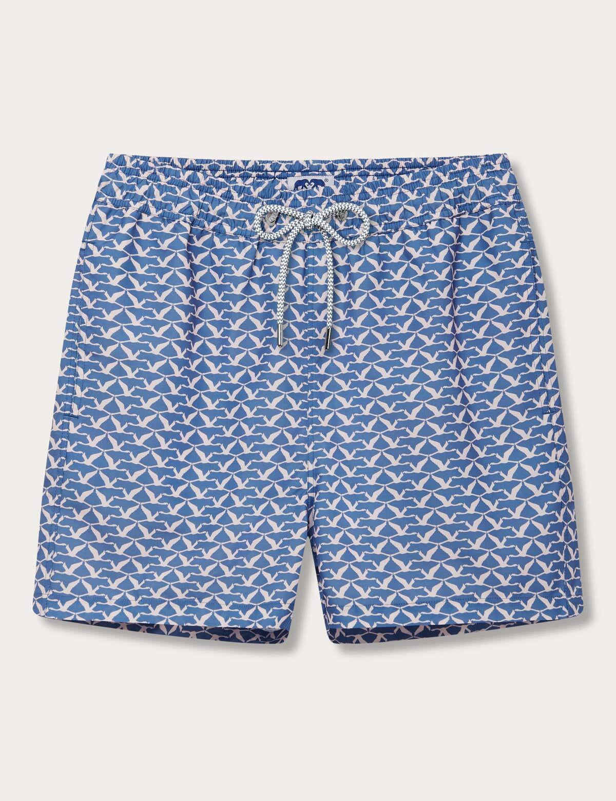 Men's Flamingo Flamboyance Staniel Swim Shorts with blue background and white flamingo print, featuring an elastic waistband with adjustable drawstring.