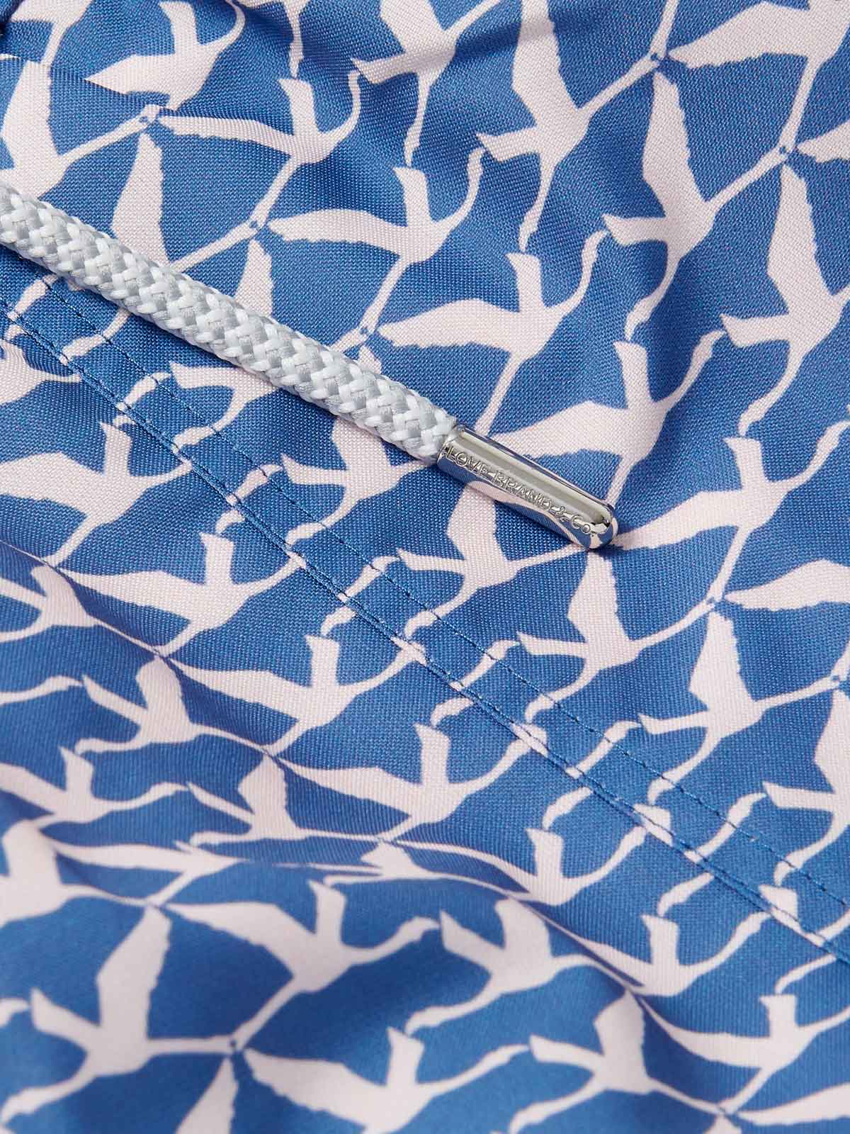 Close-up image of the Men's Flamingo Flamboyance Staniel Swim Shorts. Patterned swim shorts featuring a blue and white flamingo print pattern, highlighting the intricate stitching and a cord detail.