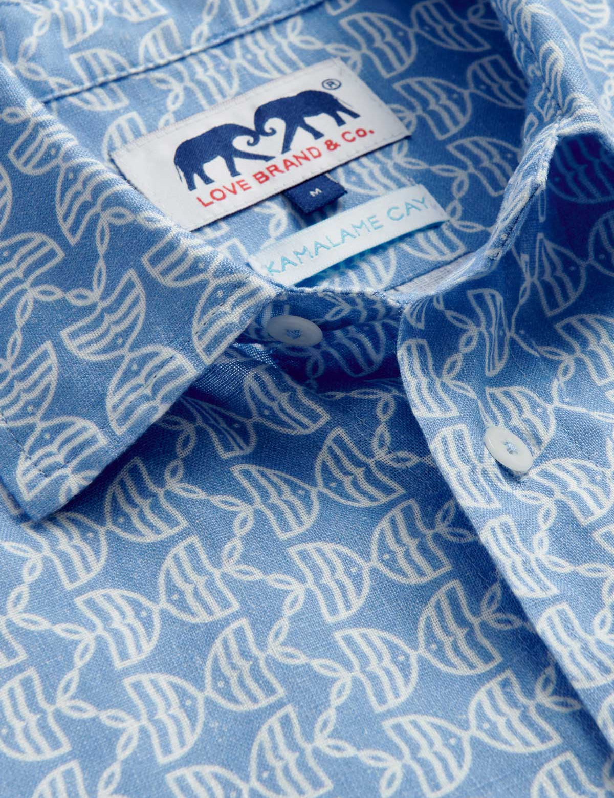 Close-up view of Men's Kissing Fish Abaco Linen Shirt. 100% linen shirt showcasing white kissing fish pattern on a blue base.