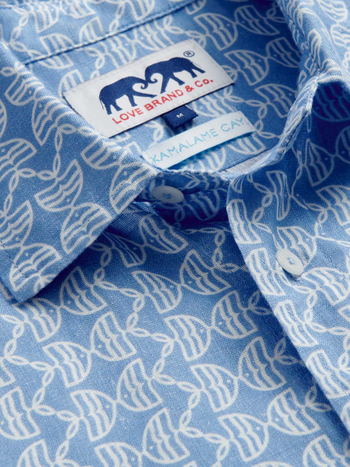 Close-up view of Men's Kissing Fish Abaco Linen Shirt. 100% linen shirt showcasing white kissing fish pattern on a blue base.