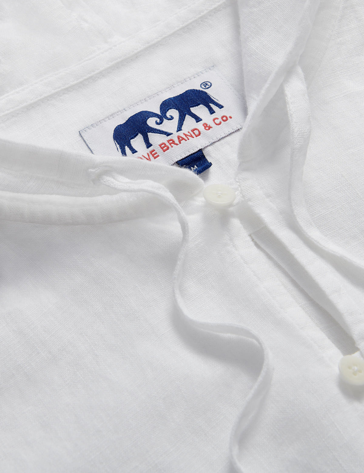 Close-up of Men's White Windermere Linen Long Sleeve Hoodie. Long-sleeved half-button-up 100% linen hoodie. 2 front pockets with a drawstring hood.