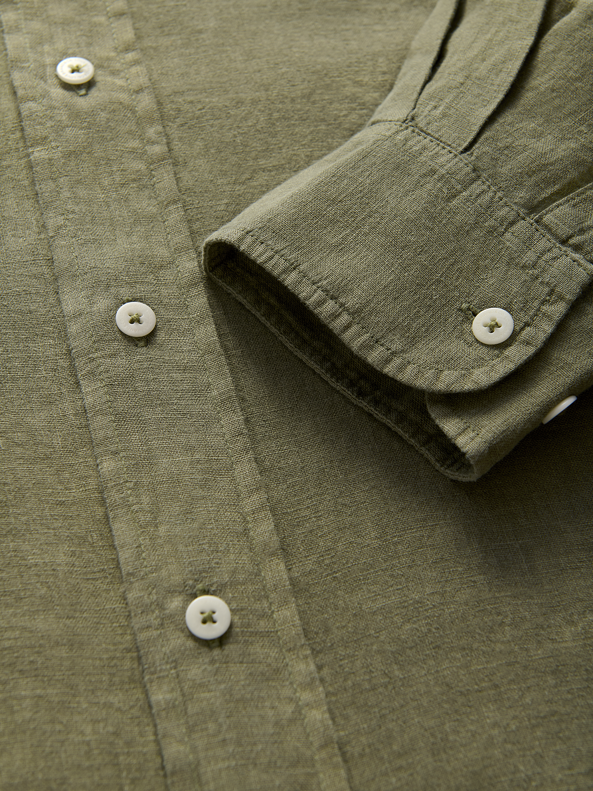 Close-up of an olive green linen shirt with buttons