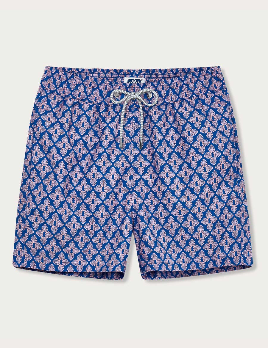 Men's Palm Paradise Staniel Swim Shorts. Patterned swim shorts featuring pastel pink Monstera leaf print on blue background.