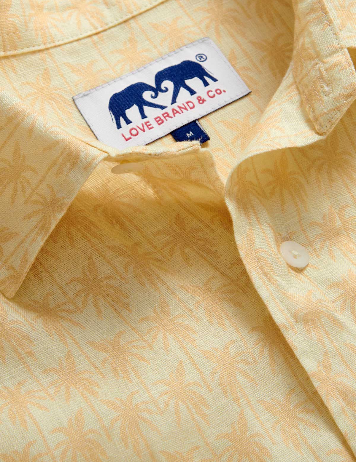 Close-up view of Men's Palm Sundowner Abaco Linen Shirt by love brand & co. Yellow and orange patterned shirt with classic collar and long-sleeves. Button-up design made from 100% linen.