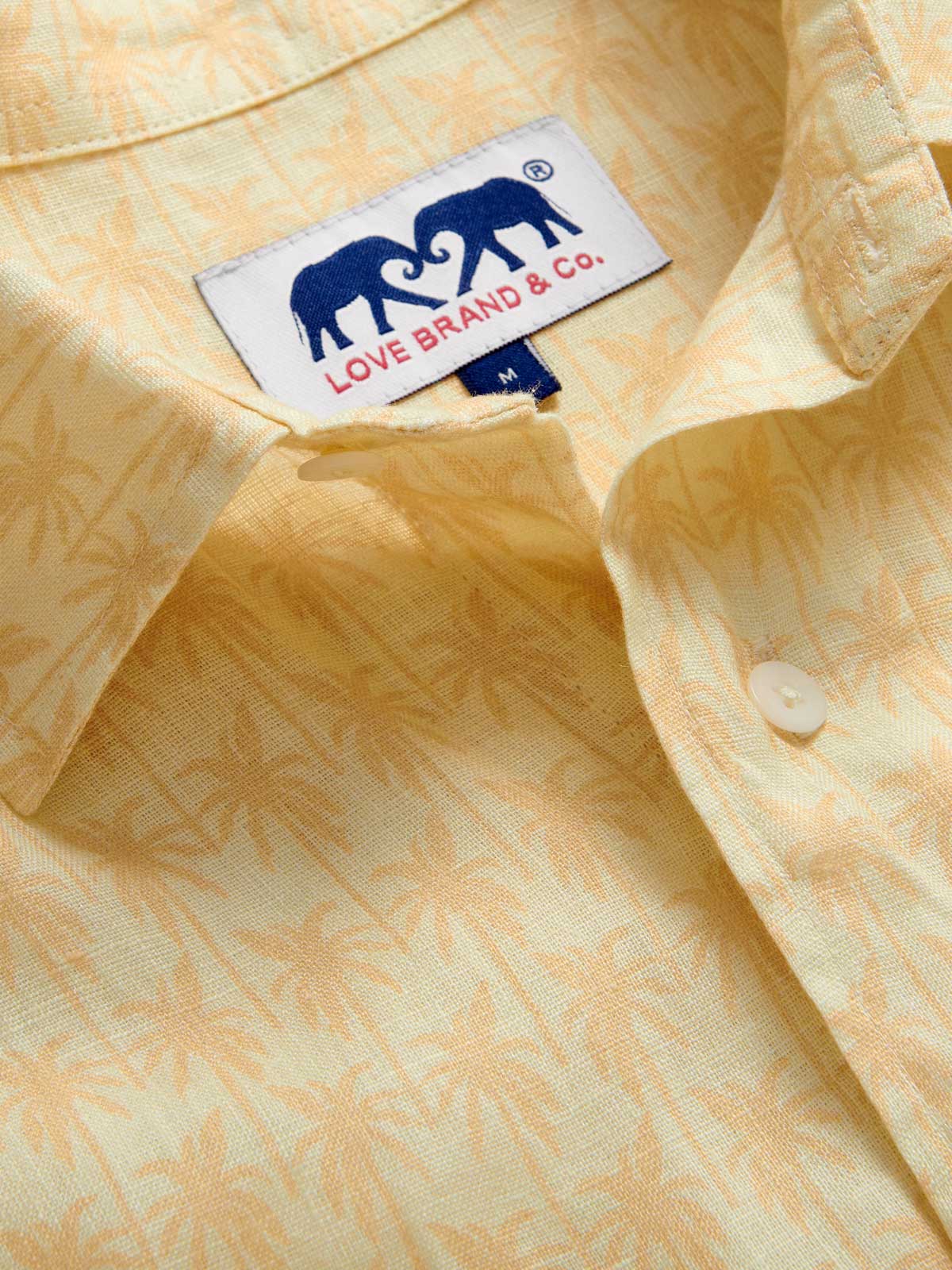 Close-up view of Men's Palm Sundowner Abaco Linen Shirt by love brand & co. Yellow and orange patterned shirt with classic collar and long-sleeves. Button-up design made from 100% linen.