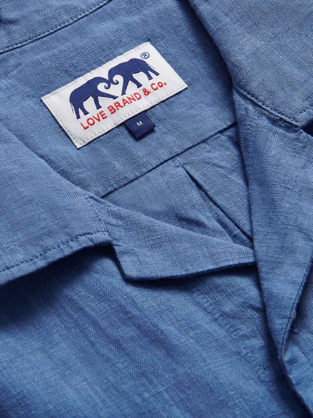 Close-up view of Men's Deep Blue Normans Linen Shirt. Blue short-sleeved linen shirt with 2 double breast pockets with a button-up design.