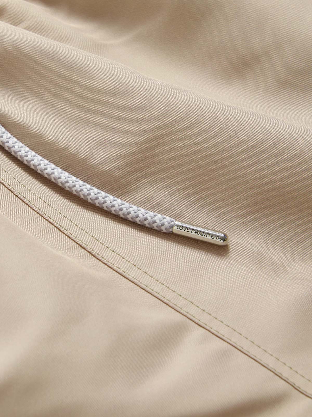 Close-up view of Men's Coconut Staniel Swim Shorts in beige colour by love brand & co. Brown swim shorts with pockets and drawstring waist.