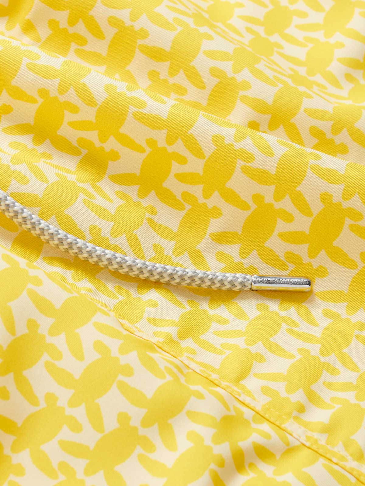 Close-up of Men's Turtle Light Staniel Swim Shorts in sunny yellow with a pattern of small turtles and a white adjustable drawstring.