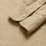 Detailed view of Men's Coconut Windermere Linen Long Sleeve Hoodie. Brown linen shirt with a drawstring hood. Crafted from 100% linen with half-button-up design and 2 large front pockets.