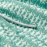 Close-up of the Men's Which Way to the Tropics Staniel Swim Shorts fabric, featuring a green pattern with swordfish dueling.