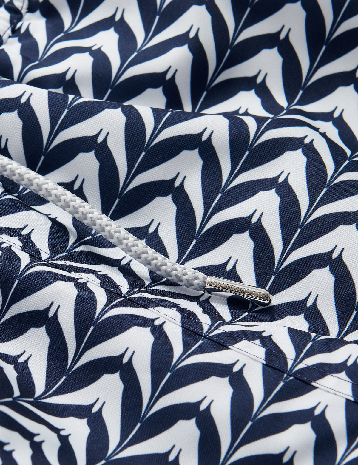 Close-up of Men's Feather Icing Staniel Swim Shorts fabric showcasing blue and white feather pattern and drawstring detail.