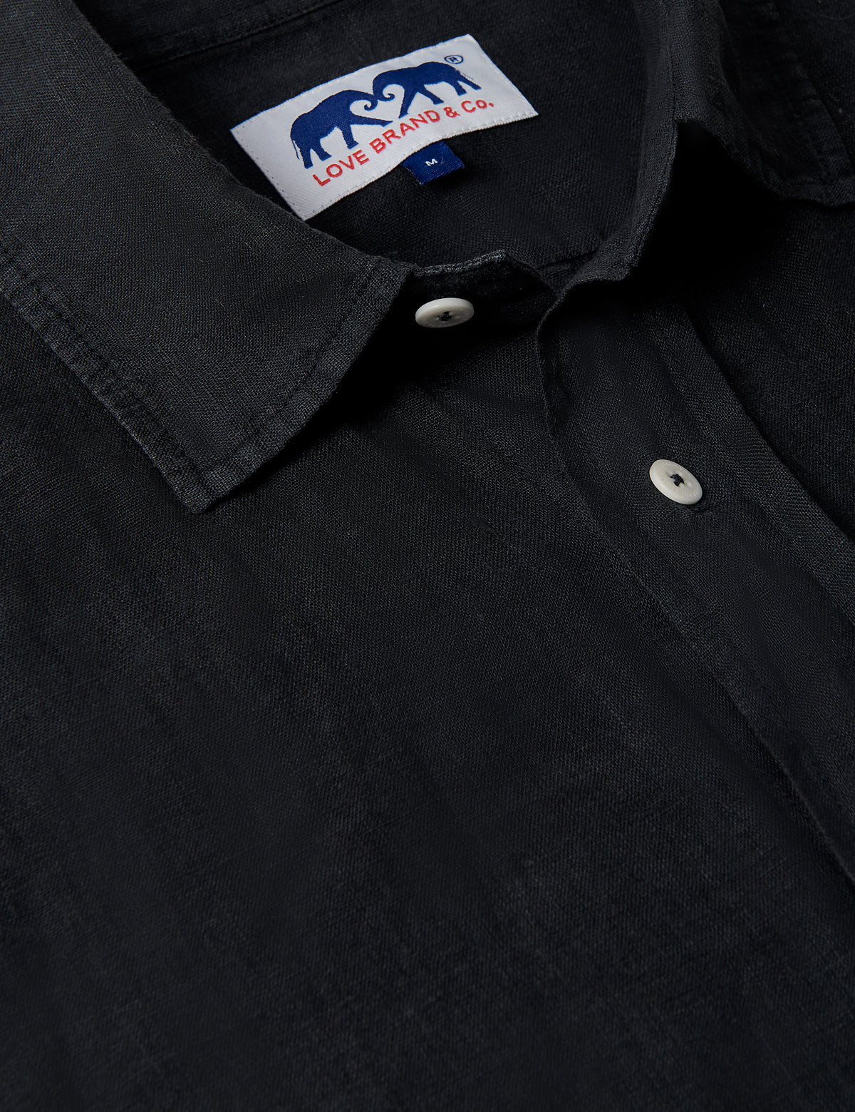 Close-up of Men's Volcanic Black Manjack Linen Shirt, showcasing collar, buttons, and Love Brand & Co. label.