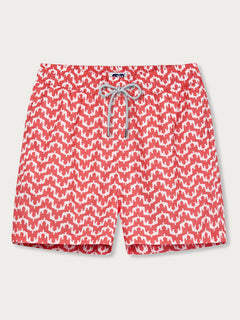 Elephant Palace Coral Staniel mens Swim Shorts front view. Patterned swim shorts featuring white elephants raising their trunks to create a pattern that resembles Indian palaces on a coral red background.