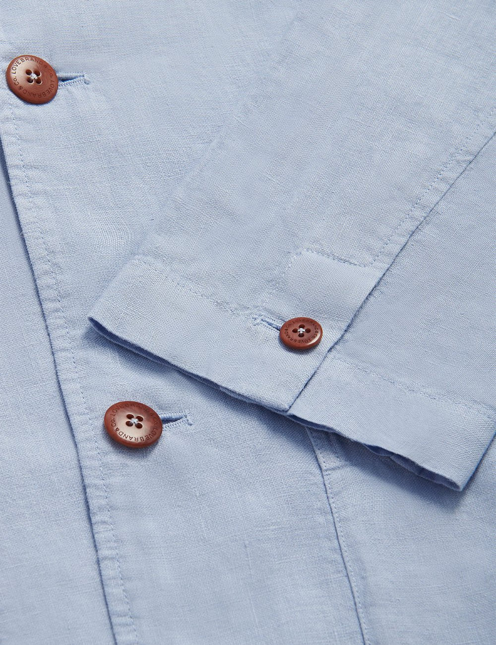 Close-up view of the Men's Sky Blue Nassau Linen Jacket. Men's linen jacket featuring light linen fabric and signature corozo nut buttons.