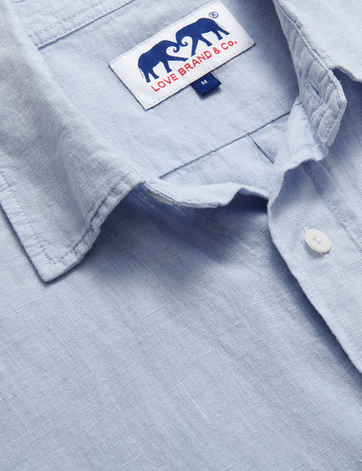 Close-up of Men's Sky Blue Manjack Linen Shirt. Men's linen shirt close-up image showcasing the soft fabric texture and brand label.