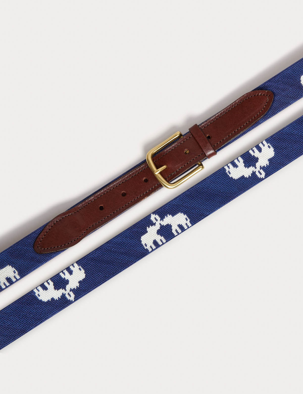 Blue needlepoint belt featuring Asian elephants with trunks up, crafted by B-Corp artisans in Haiti, with genuine leather and a solid brass buckle.