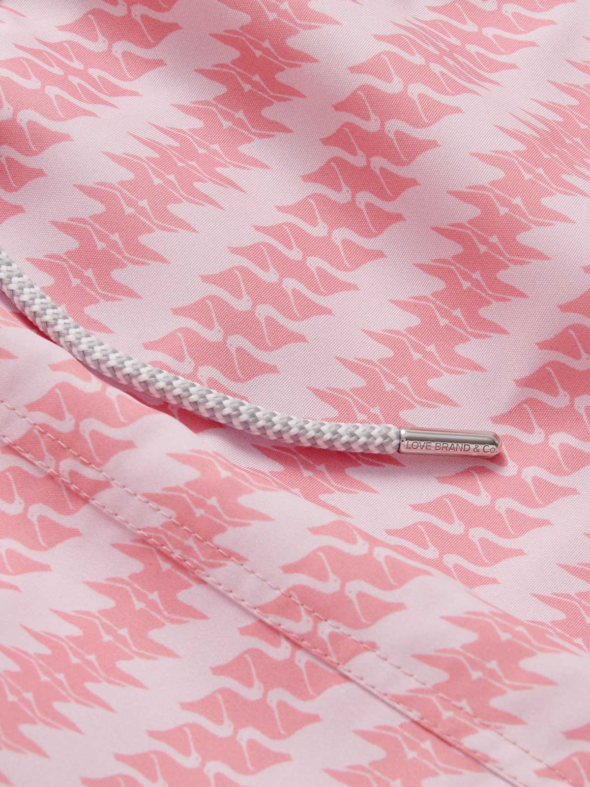 Close-up of the patterned fabric and drawstring detail of the Men's Roseate Spoonbill Staniel Swim Shorts. Patterned swim shorts showcasing a pink and white design inspired by the graceful motion of the roseate spoonbill. Made from 100% recycled, quick-drying fabric for comfort and style.