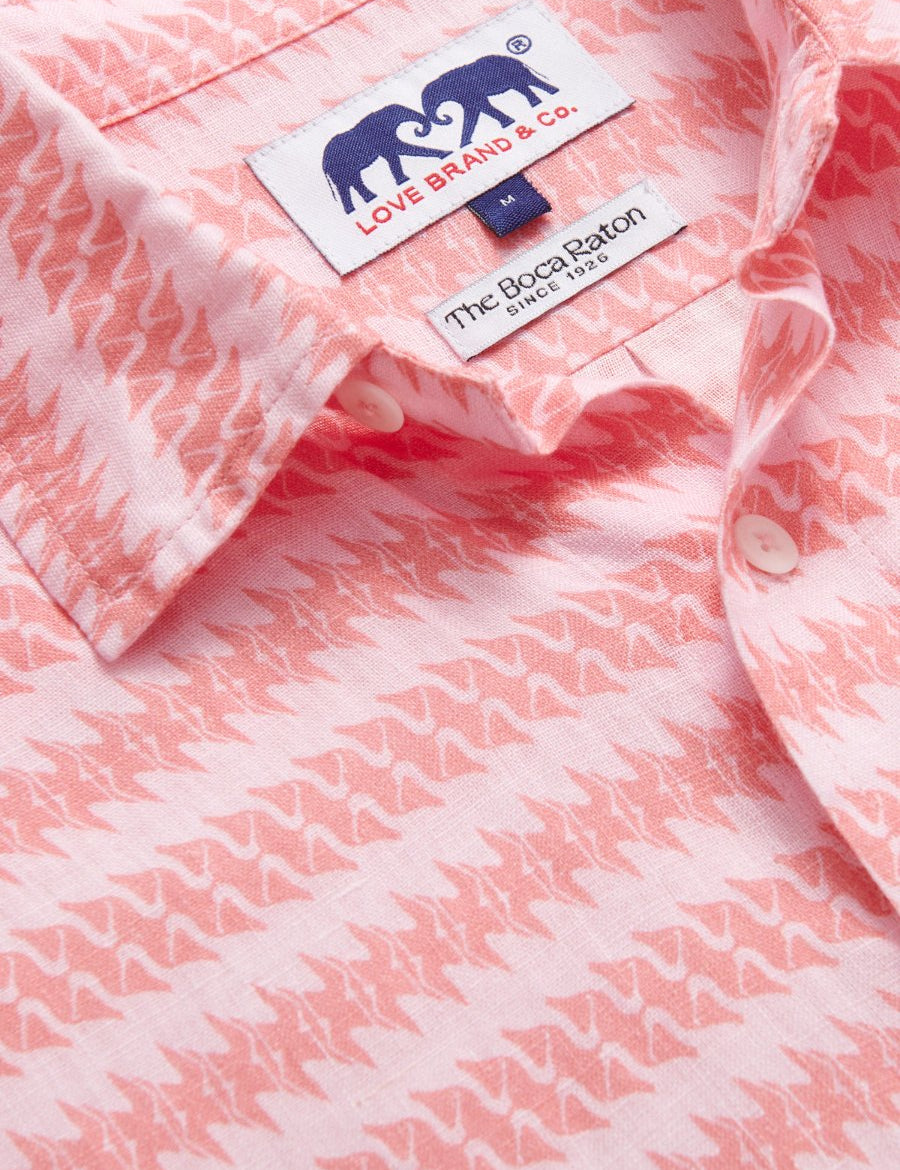 Close-up of Roseate Spoonbill Abaco men's Linen Shirt displaying a vibrant pink pattern featuring the Roseate Spoonbill bird and tags from LOVE BRAND & Co. and The Boca Raton. Old money shirts made from 100% linen.