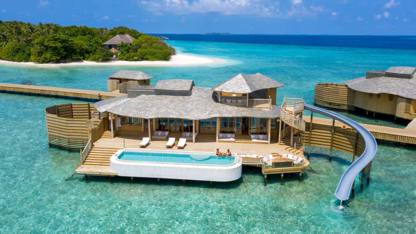 Overwater bungalows with a pool and slide in a tropical setting