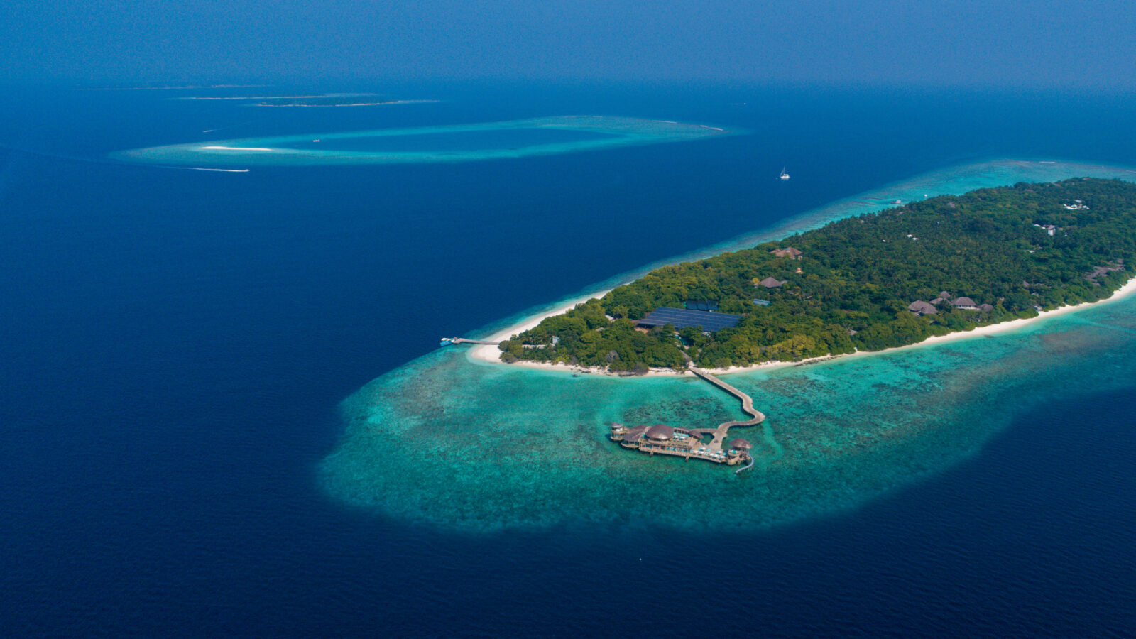 Aerial view of tropical island Soneva Fushi with lush greenery and clear blue water.