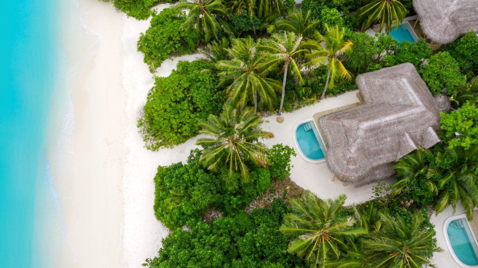 Aerial view of tropical resort, Soneva Fushi, with palm trees and pools.