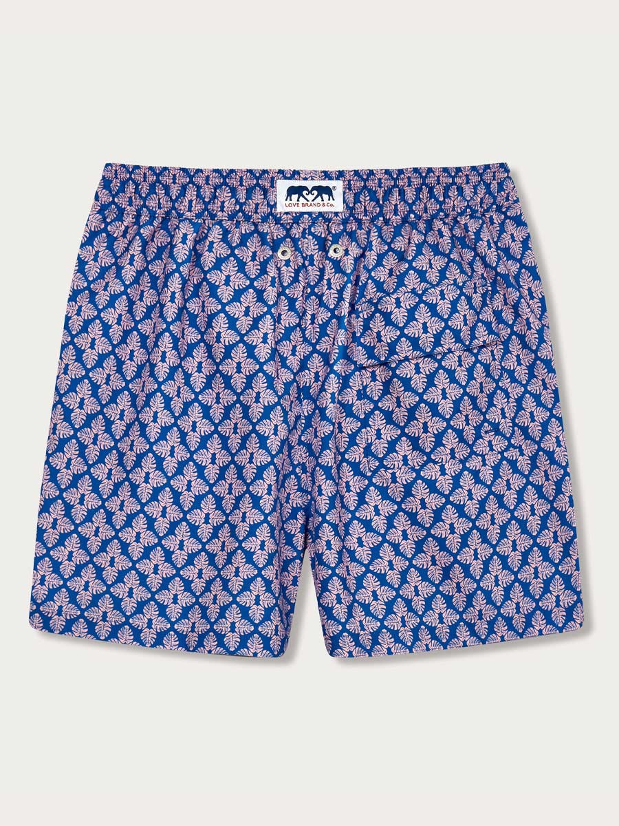 Men's Palm Paradise Staniel Swim Shorts with pastel pink Monstera leaf print on blue background.