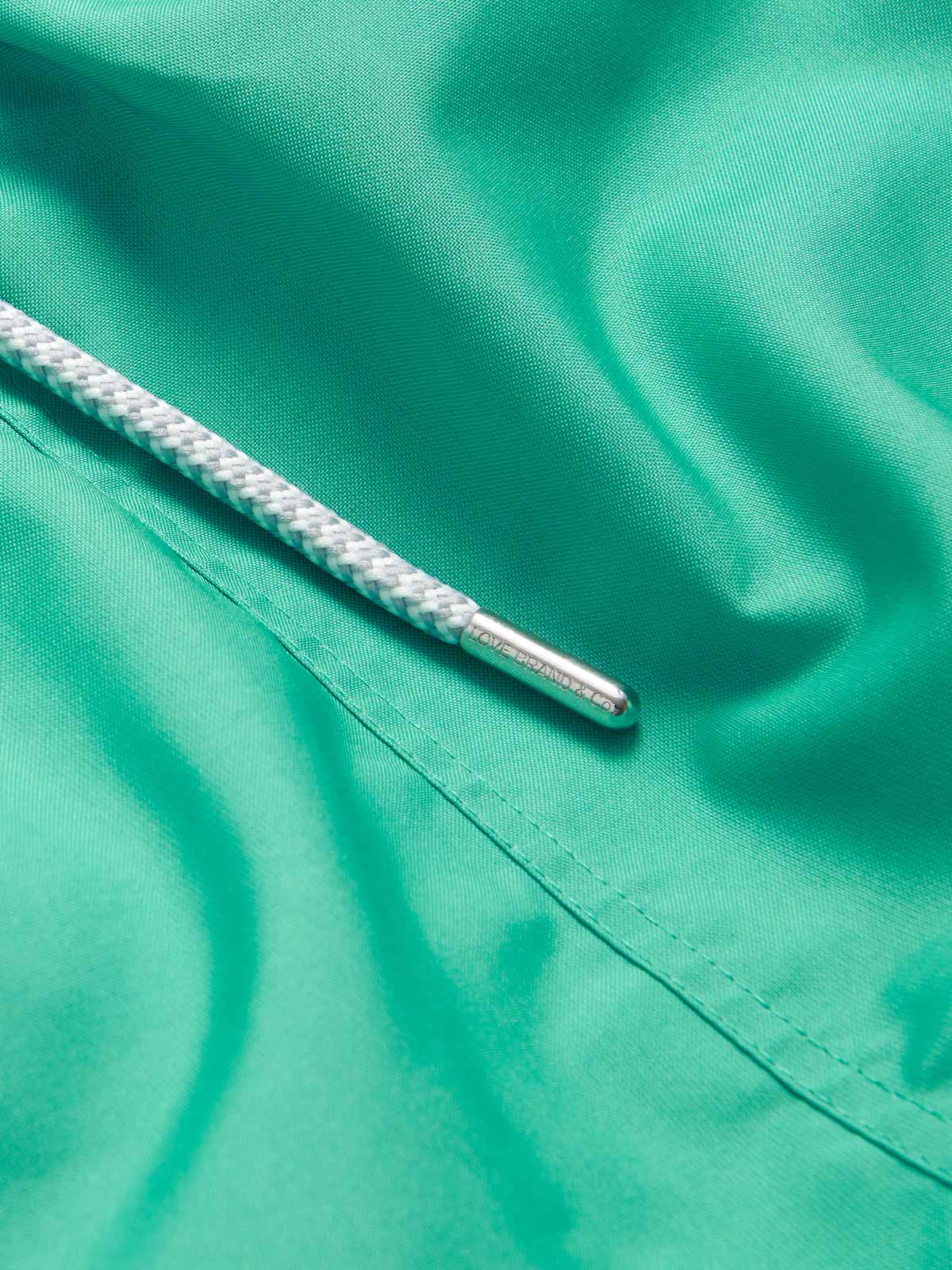 Close-up of Men's Sicilian Green Staniel Swim Shorts in vibrant green fabric showing a white drawstring with silver aglet.