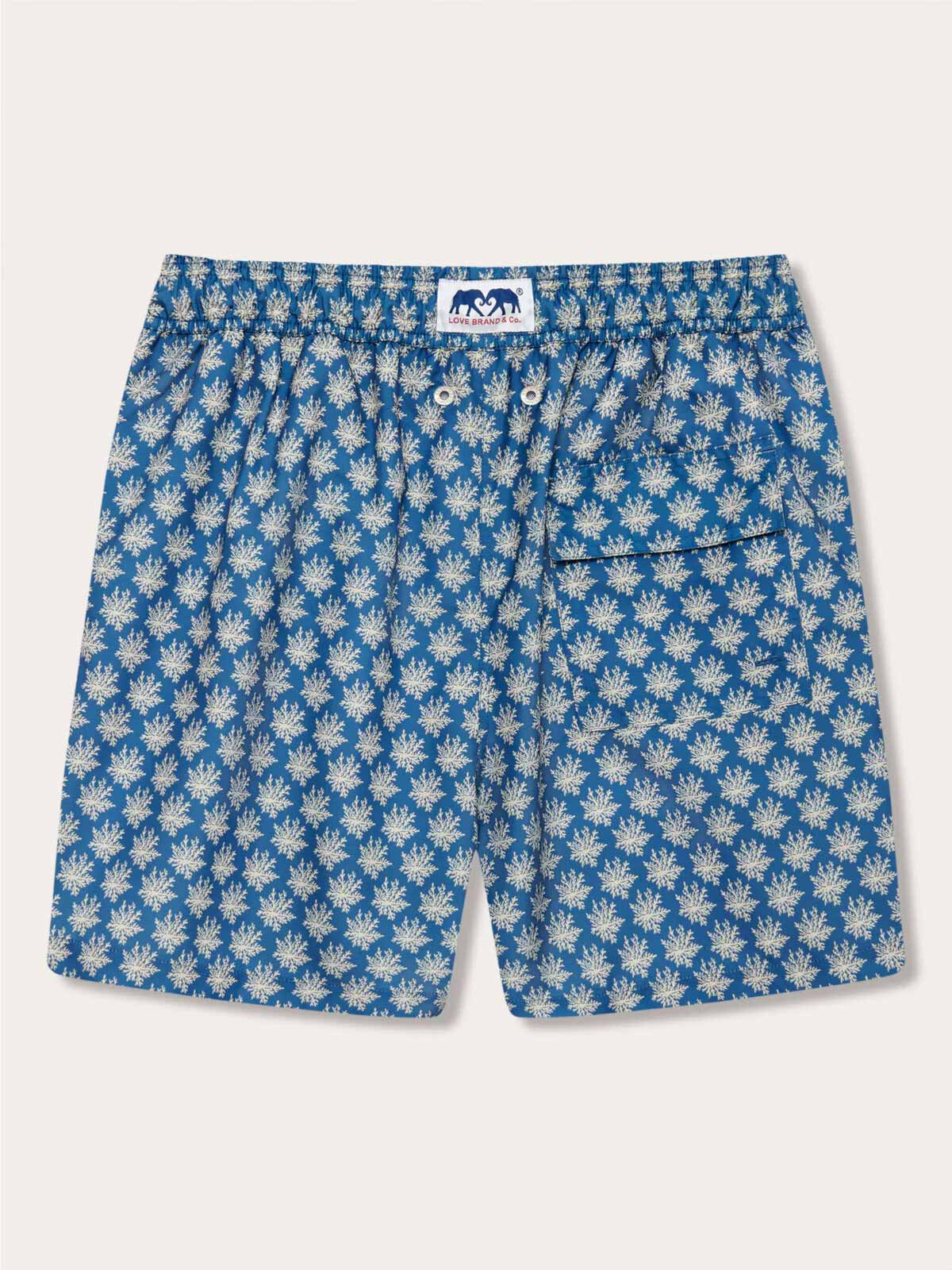 Men's Coral Clusters Staniel Swim Shorts with luxurious stone-shaded coral patterns set against a blue background, featuring an elastic waistband and a back pocket.